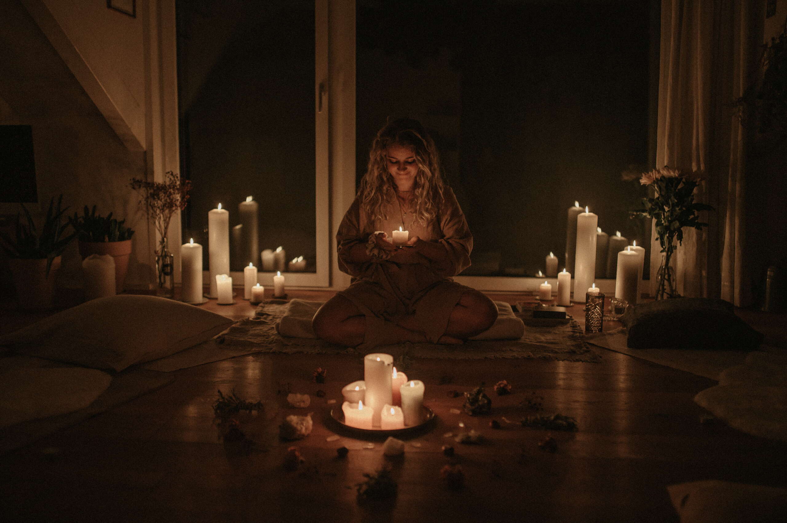 Frau im Sitzkreis umgeben von Kerzen