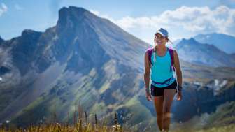 Junge Frau in sommerlicher Kleidung wandert auf der 7-Gipfel-Tour am Flumserberg