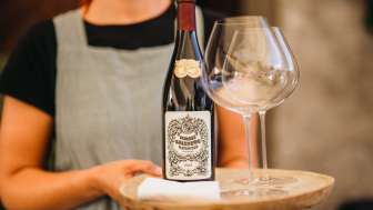 Weinservice Schloss Salenegg Frau serviert eine Flasche Wein mit Gläsern