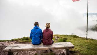 Wandern bei jedem Wetter Pärchen sitzt auf einer Bank im Nebel