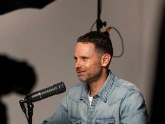 Moderator Manuel Rothmund sitzt im Podcast-Studio vor dem Podcast-Mikrofon