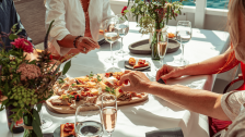 Ein reichhaltiges Apero-Plättli wird auf dem Walenseeschiff serviert. Mehrere Personen sitzen am Tisch, der mit Blumen und Weingläsern bestückt ist.